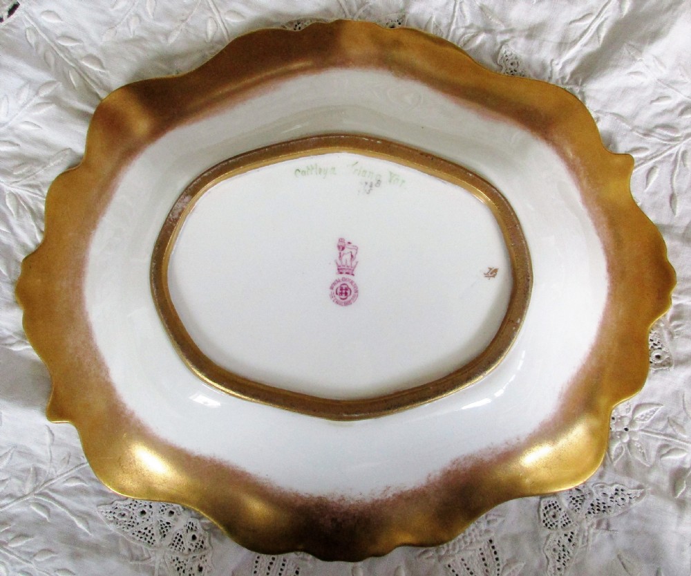 An oval antique porcelain dish featuring hand-painted pink orchids on a pale green ground with a gilded scrolled rim. View III