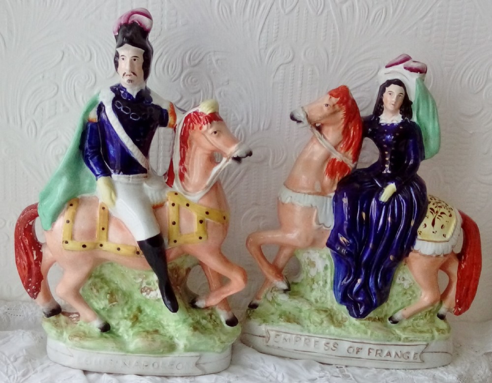 A pair of Victorian Staffordshire ceramic equestrian figures depicting Louis Napoleon and the Empress of France mounted on chestnut horses with blue and green details.