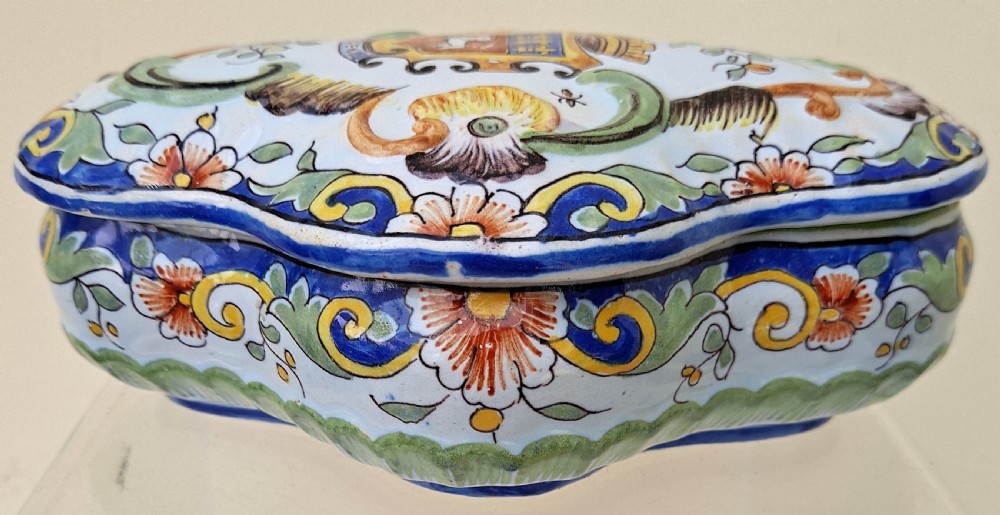 A shaped hand-painted French faience lidded trinket box with polychrome scroll and floral decoration on an off-white glaze. View VIII