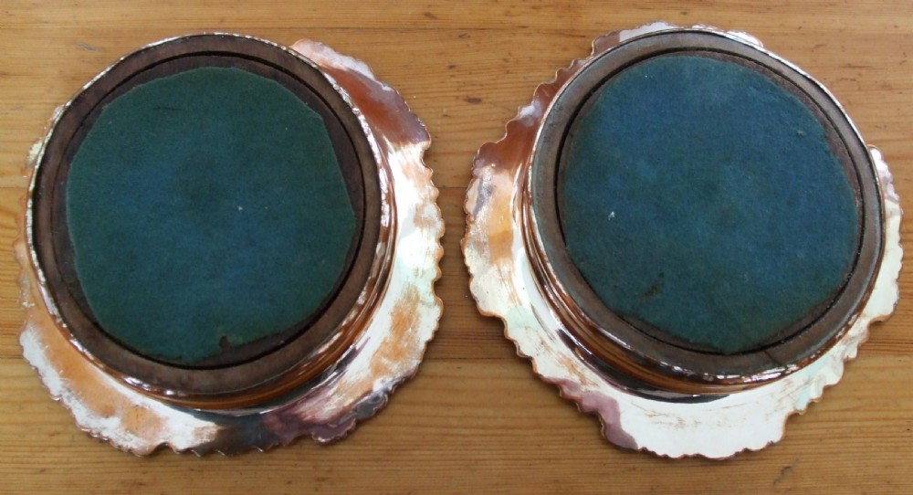A pair of antique Georgian Old Sheffield Plate wine coasters featuring ornate relief borders and turned wood centres with exposed copper tone. View III