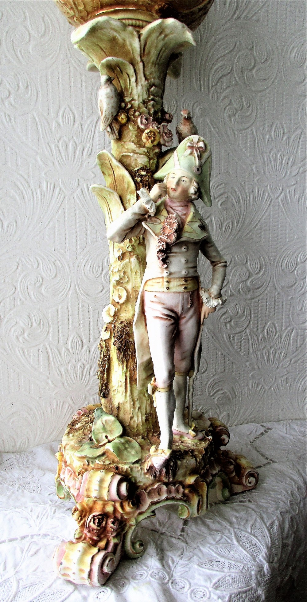 An antique Victorian porcelain oil lamp featuring a sculpted male figurine base, relief reservoir, brass burner, and a fluted green glass shade. View II