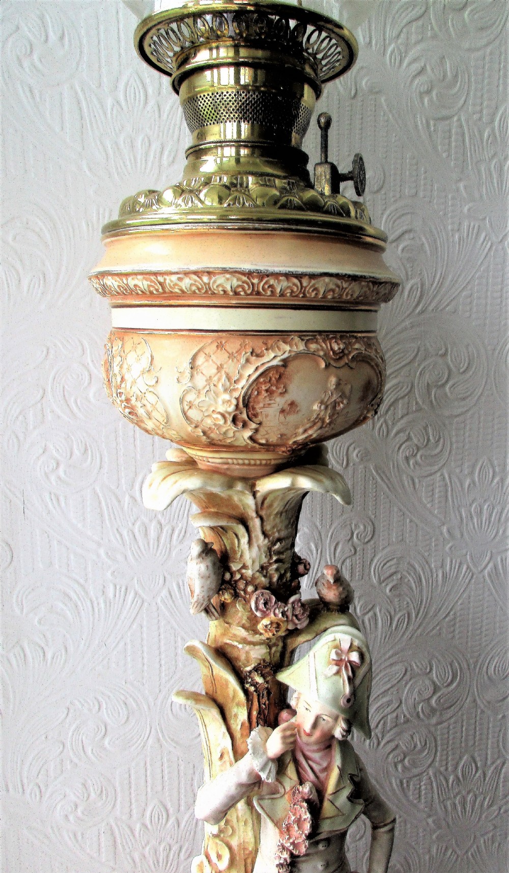 An antique Victorian porcelain oil lamp featuring a sculpted male figurine base, relief reservoir, brass burner, and a fluted green glass shade. View VI