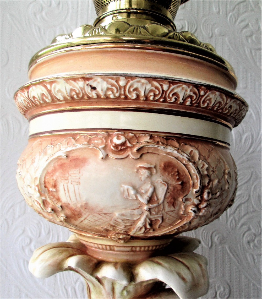 An antique Victorian porcelain oil lamp featuring a sculpted male figurine base, relief reservoir, brass burner, and a fluted green glass shade. View VII