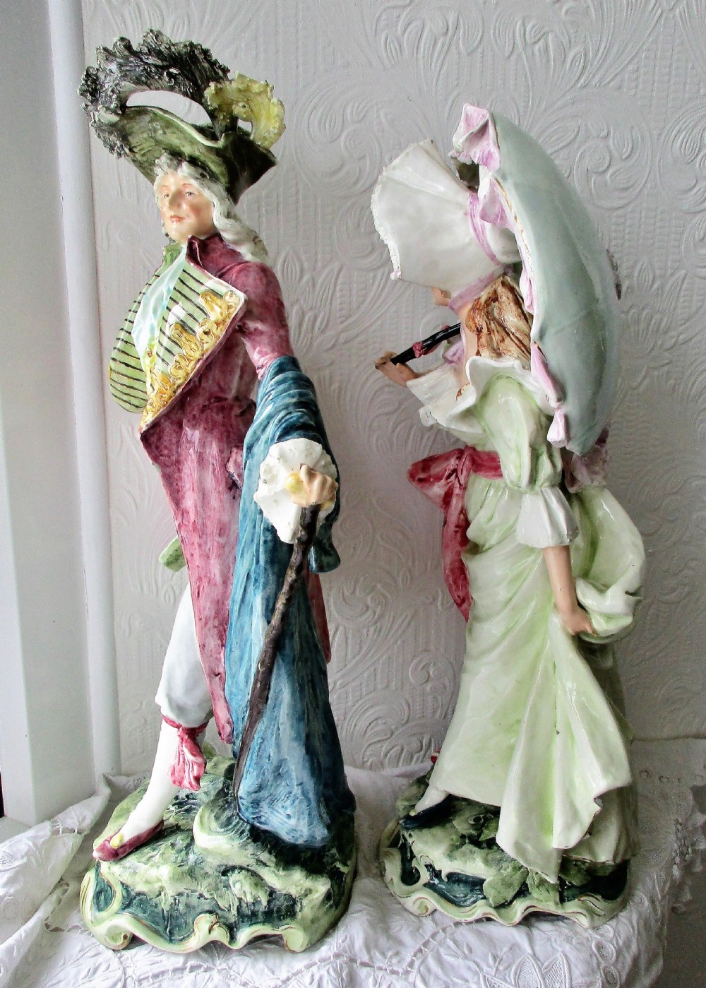 A pair of hand-painted French faience ceramic figurines depicting an 18th-century gentleman and a lady holding a parasol. View II
