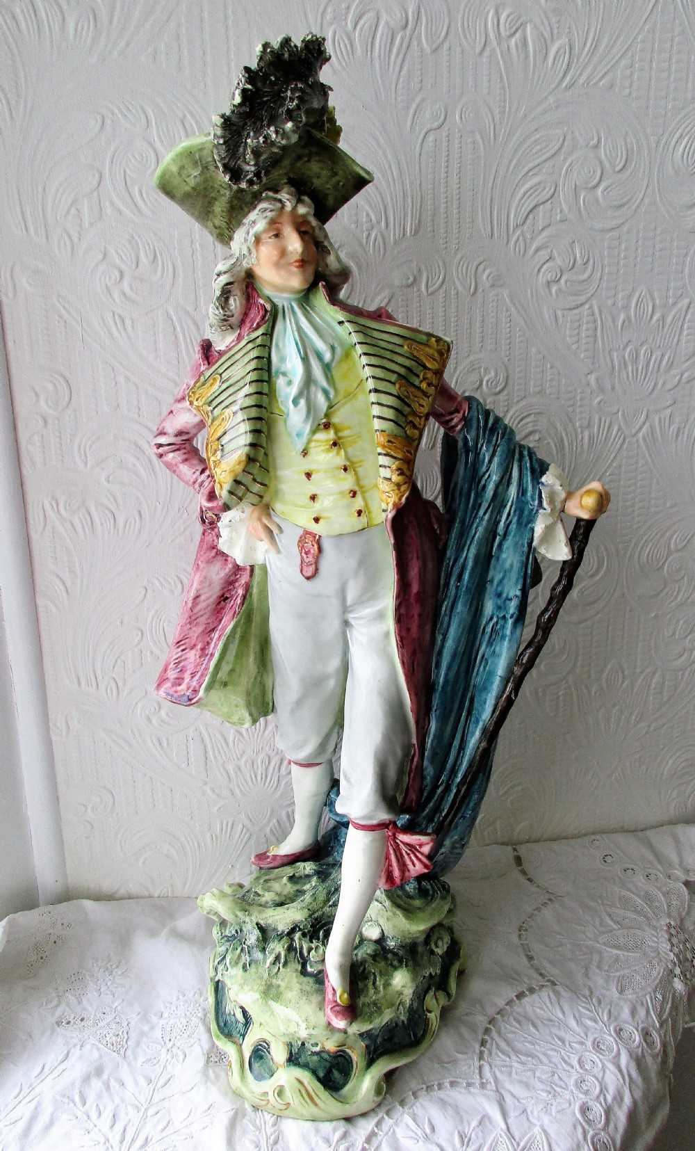 A pair of hand-painted French faience ceramic figurines depicting an 18th-century gentleman and a lady holding a parasol. View V