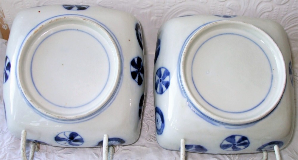A pair of square Japanese Imari porcelain dishes featuring underglaze blue landscape scenes encircled by iron-red, green, and gold enamel borders. View III