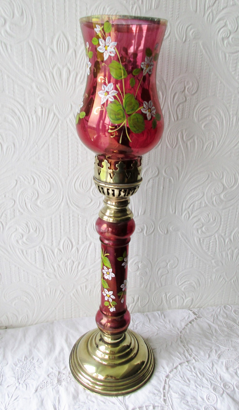 A pair of Victorian brass candle lamps featuring hand-painted floral enamel on red cranberry glass shades and stems. View II