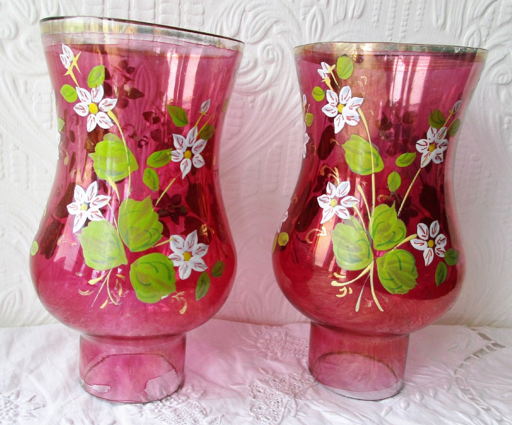 A pair of Victorian brass candle lamps featuring hand-painted floral enamel on red cranberry glass shades and stems. View VII