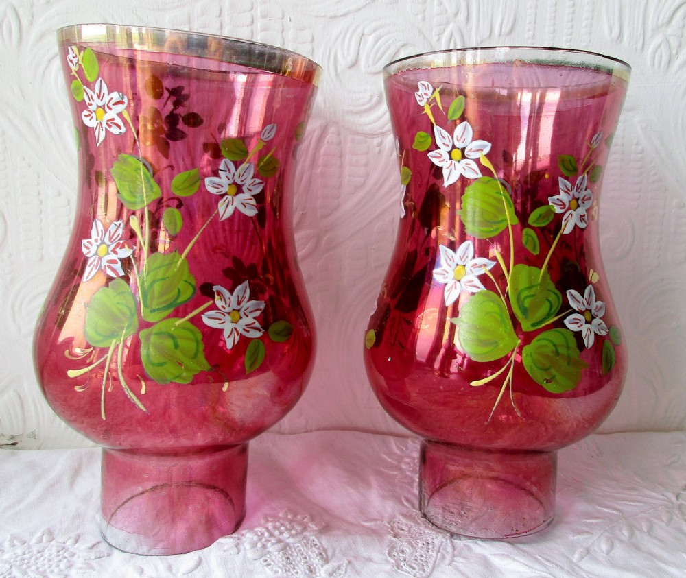 A pair of Victorian brass candle lamps featuring hand-painted floral enamel on red cranberry glass shades and stems. View VIII