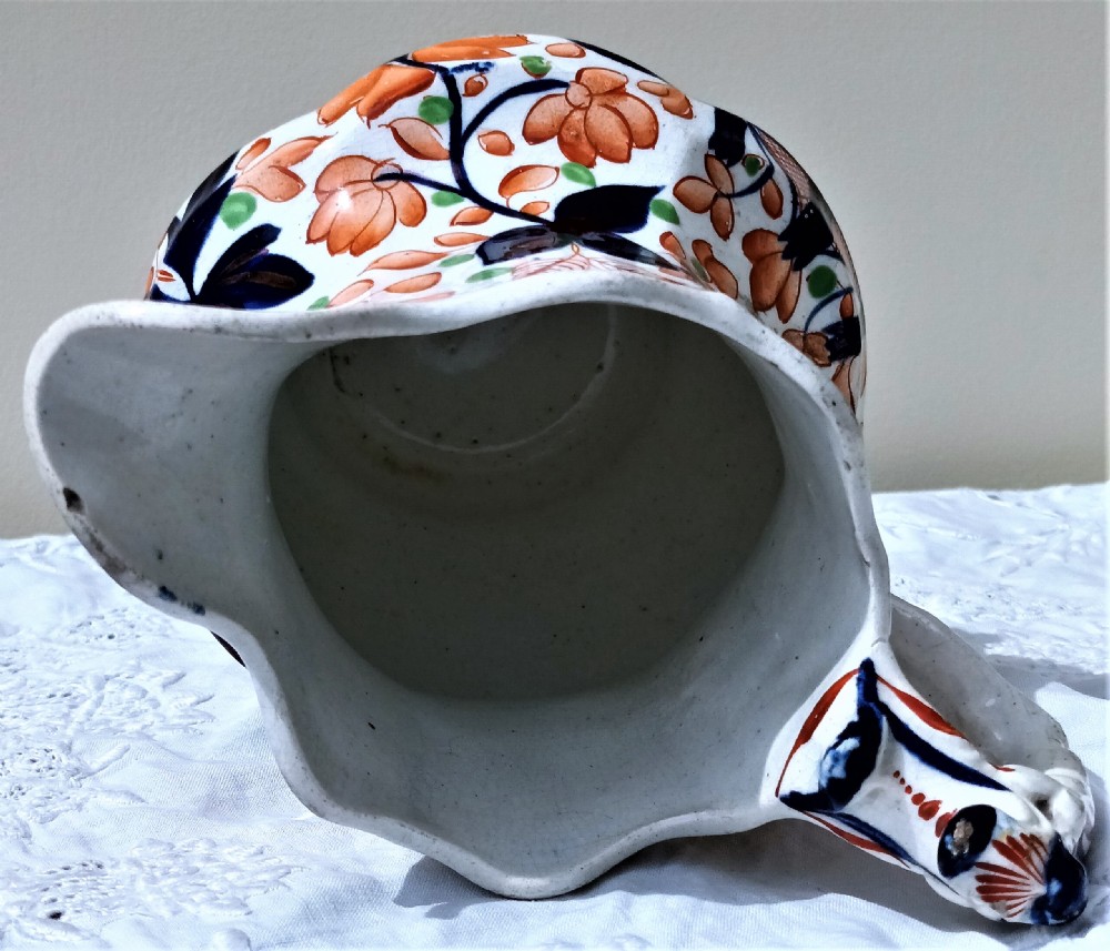 An antique Victorian Gaudy Welsh earthenware jug decorated with hand-painted orange floral motifs, cobalt blue details, a scalloped rim, and a molded handle. View V
