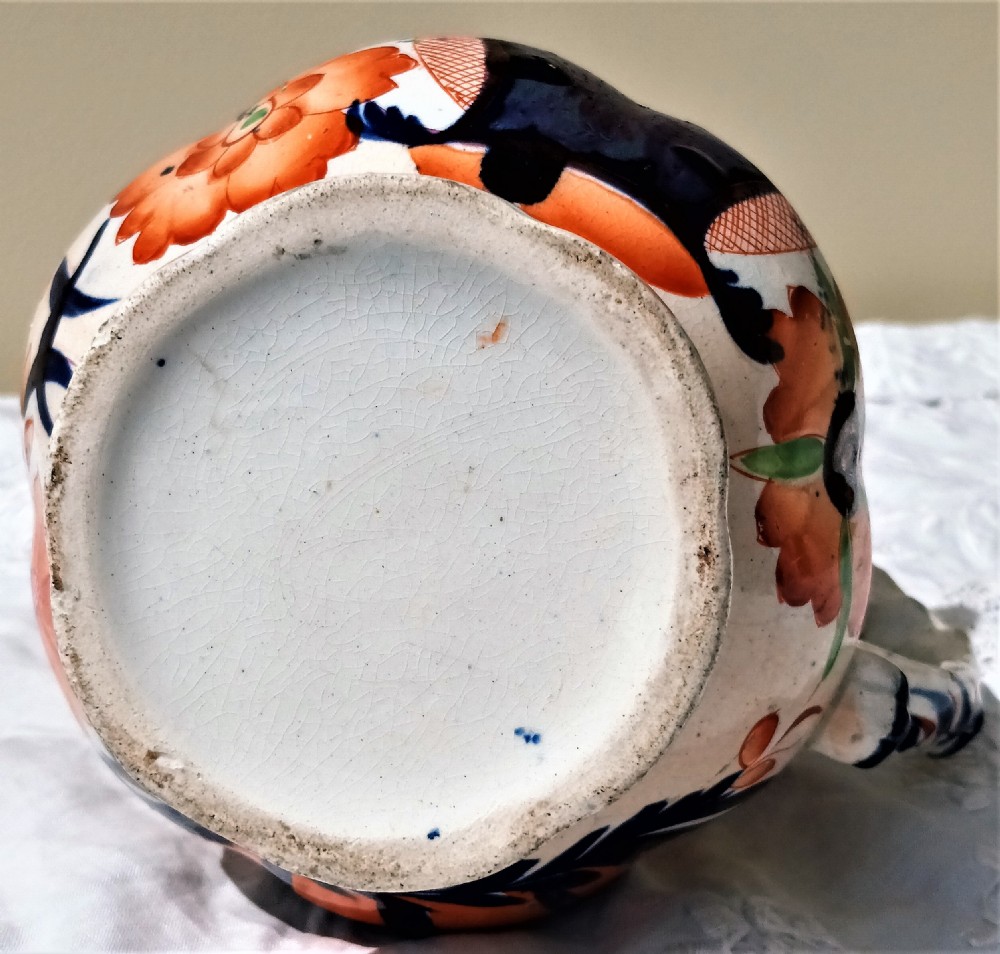 An antique Victorian Gaudy Welsh earthenware jug decorated with hand-painted orange floral motifs, cobalt blue details, a scalloped rim, and a molded handle. View VI