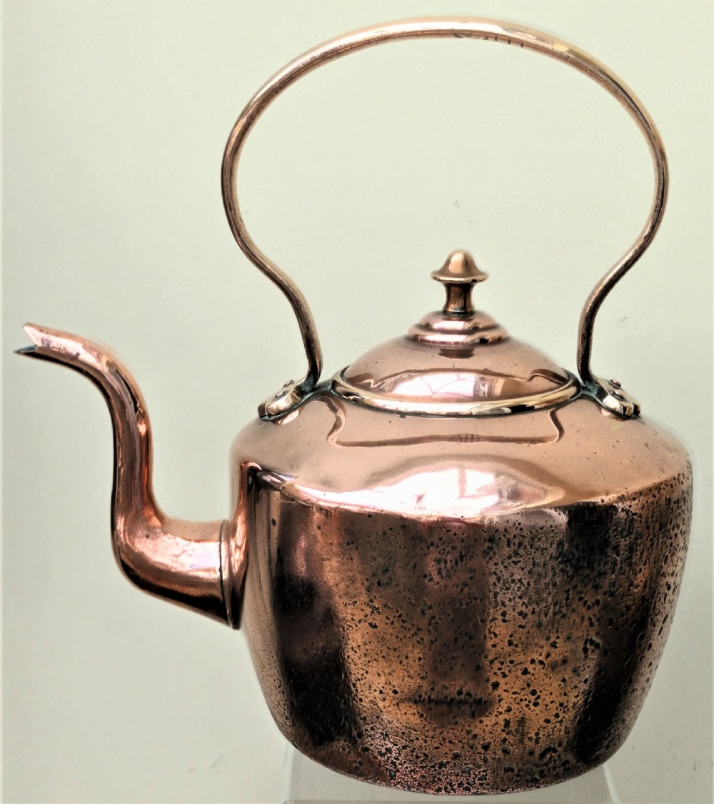 An antique Victorian copper kettle featuring a gooseneck spout, a fixed overhead loop handle, and a domed lid topped with a brass finial.