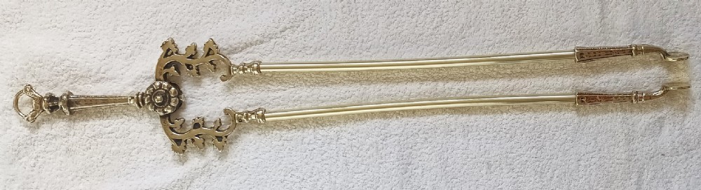 A set of three polished brass Victorian fire irons comprising a shovel with pierced detailing, a poker, and a pair of tongs with decorative scrollwork handles. View VIII
