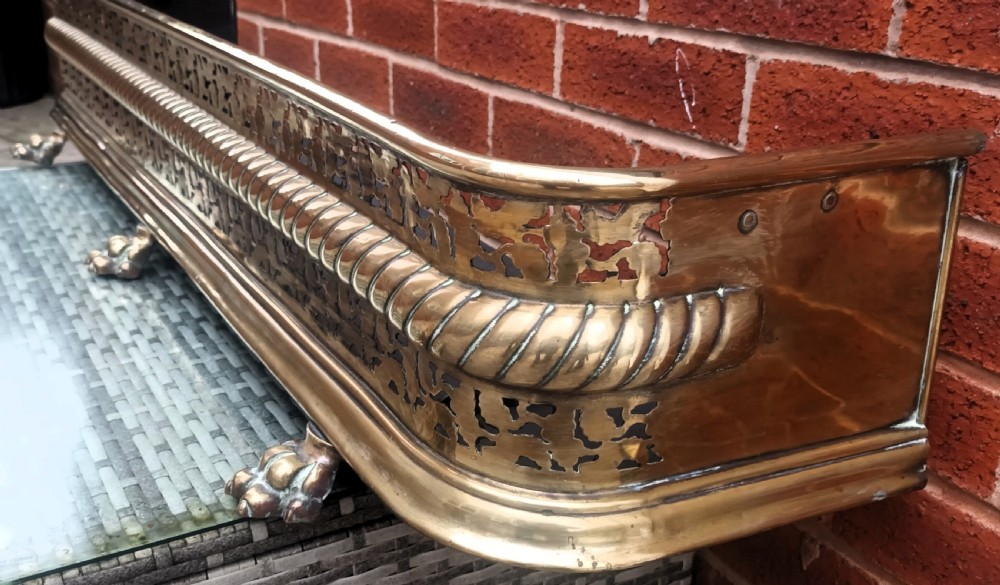 A Victorian pierced brass fireplace fender with central rope-twist moulding, pierced fretwork bands, and cast paw feet. View III