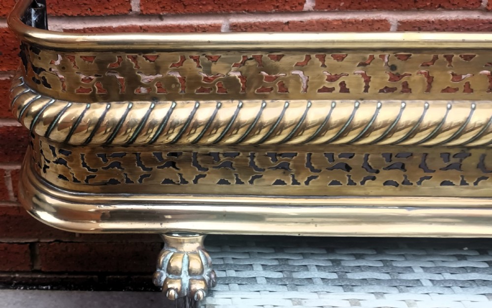 A Victorian pierced brass fireplace fender with central rope-twist moulding, pierced fretwork bands, and cast paw feet. View IV