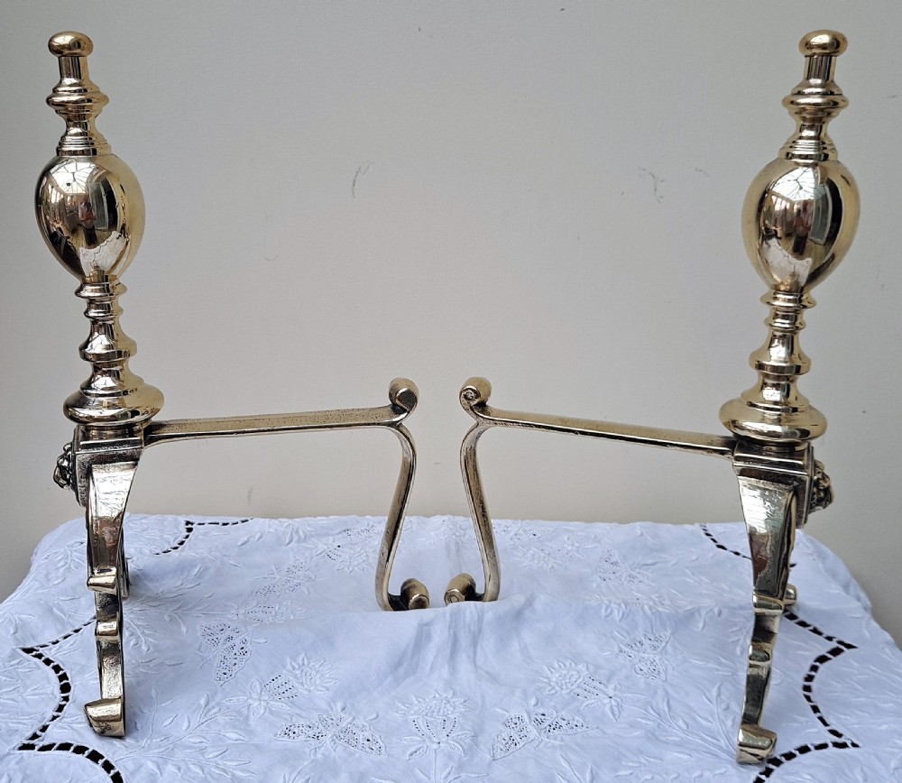 Pair of polished Victorian cast brass andirons featuring urn finials, relief lion mask detail, and scrolling feet. View II