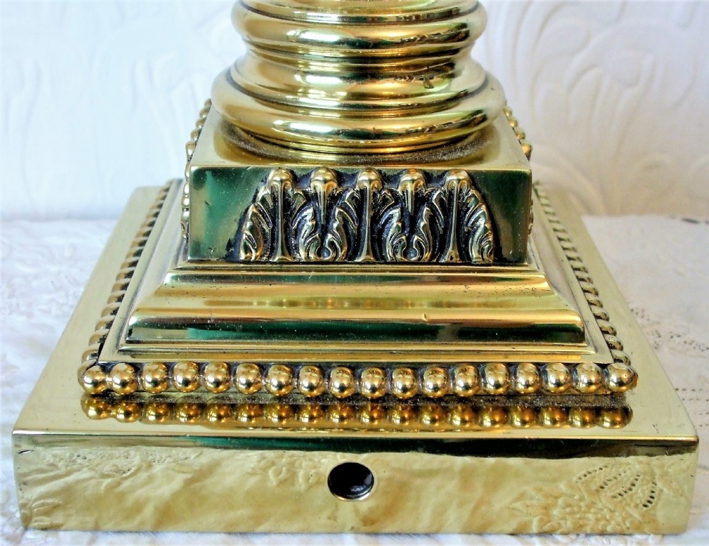 An antique Victorian oil lamp featuring a polished brass Ionic column base, an etched green glass reservoir, a frilled shade, and a glass chimney. View V