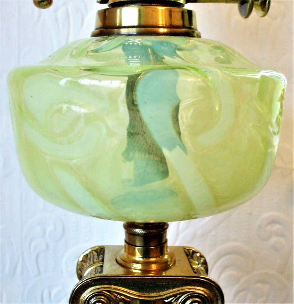 An antique Victorian oil lamp featuring a polished brass Ionic column base, an etched green glass reservoir, a frilled shade, and a glass chimney. View VII
