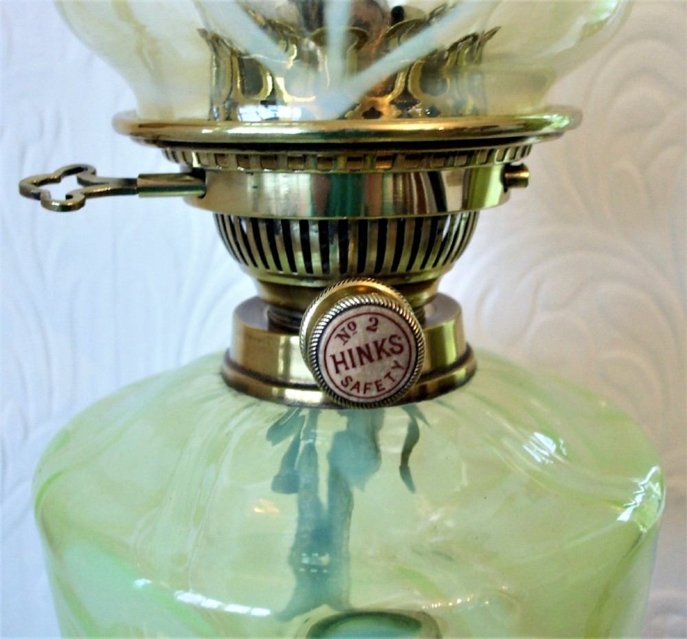 An antique Victorian oil lamp featuring a polished brass Ionic column base, an etched green glass reservoir, a frilled shade, and a glass chimney. View VIII
