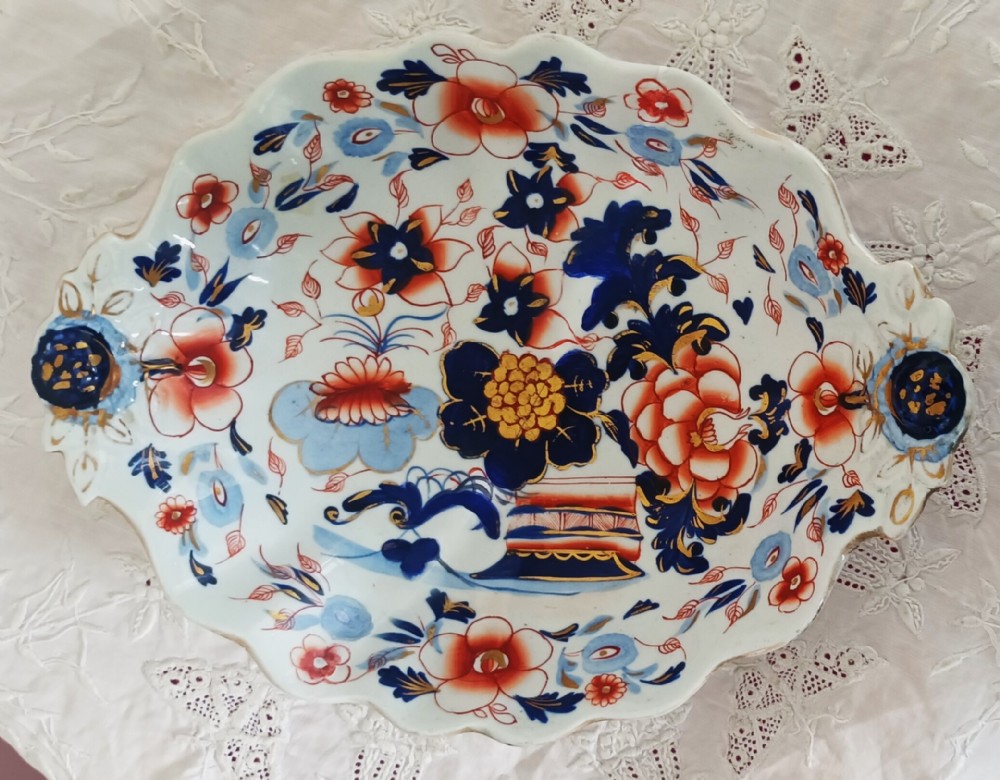 An oval English Georgian ironstone china low comport featuring a scalloped rim, integrated handles, and hand-painted Japan pattern florals in cobalt blue, rust red, and gilt accents.