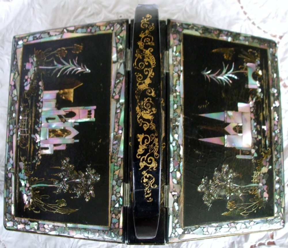 A Victorian black lacquer papier-mache needlework casket featuring mother-of-pearl inlay, gilded scrollwork, a sloped hinged lid, and a central arch handle. View II