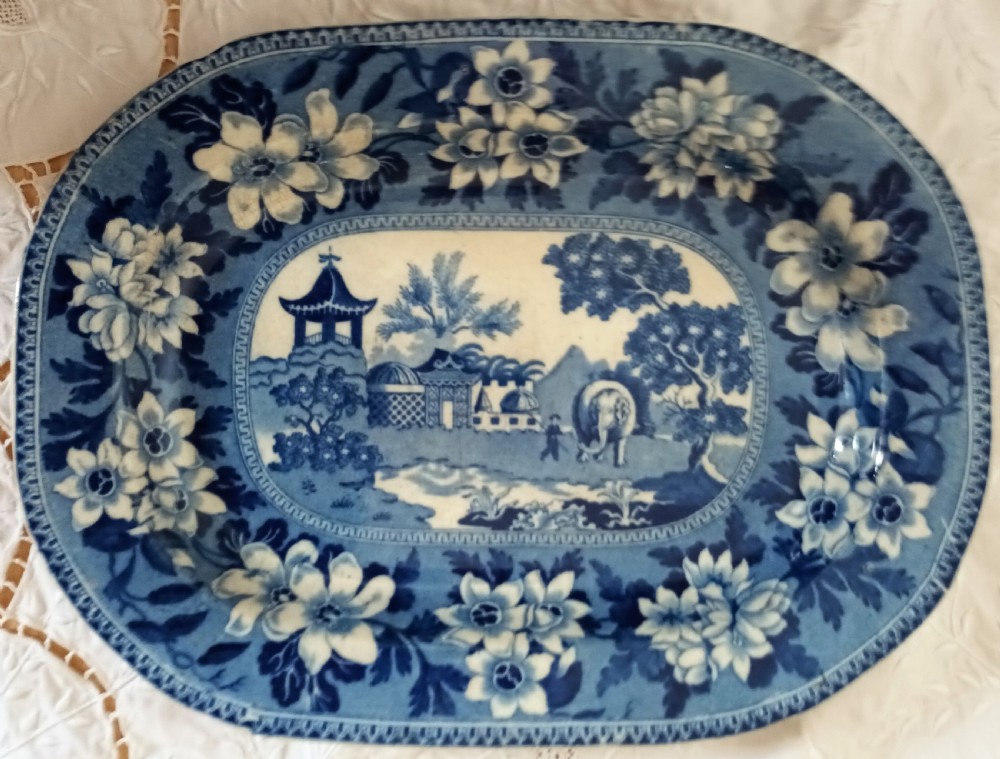 An oval Georgian earthenware platter featuring a blue and white underglaze transfer pattern depicting an elephant and oriental architecture framed by a bold floral border.