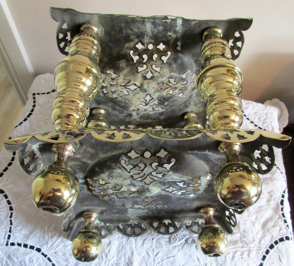 A square two-tier Victorian brass trivet stand featuring pierced fretwork surfaces and turned baluster column supports. View III