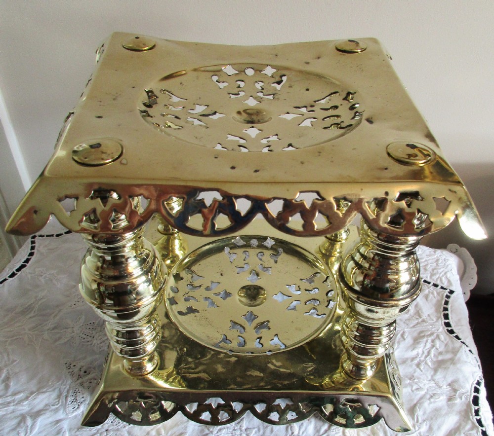 A square two-tier Victorian brass trivet stand featuring pierced fretwork surfaces and turned baluster column supports. View IV