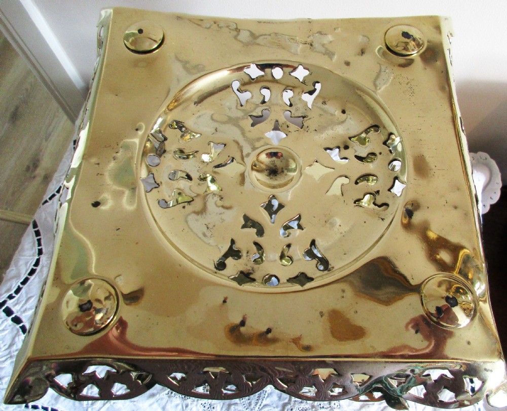 A square two-tier Victorian brass trivet stand featuring pierced fretwork surfaces and turned baluster column supports. View V