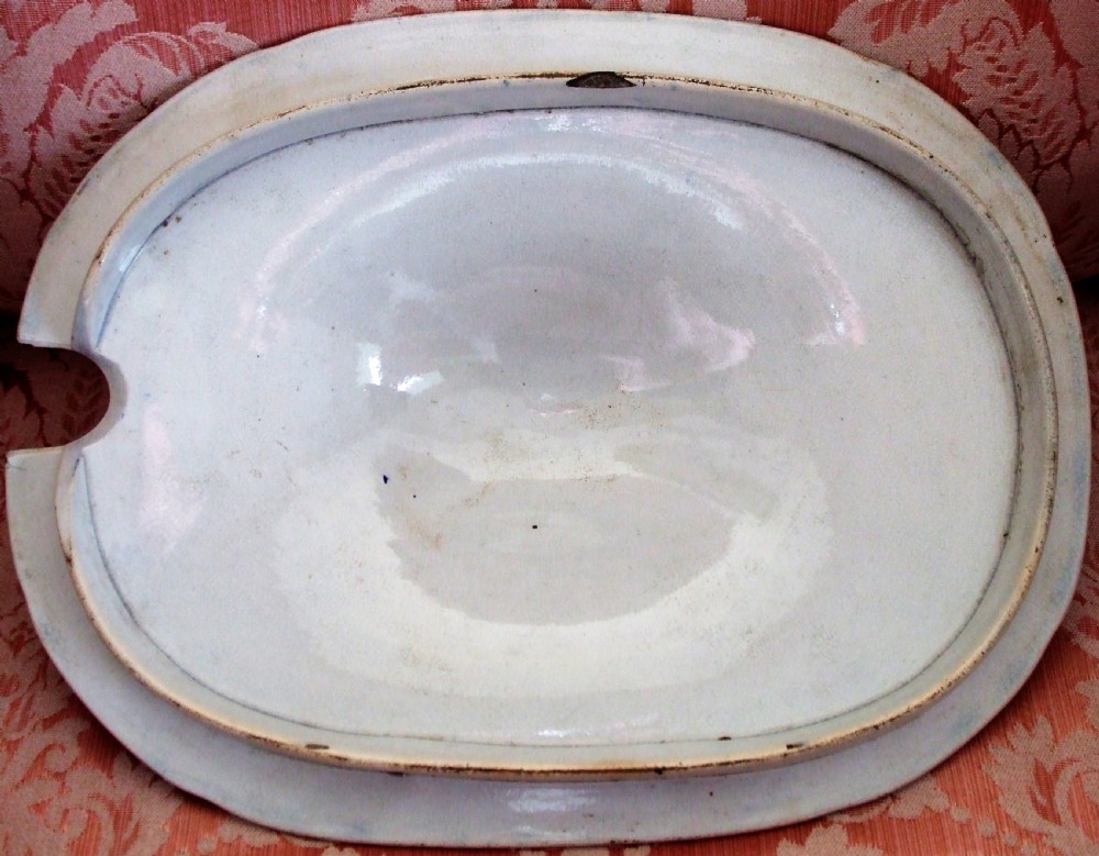 An oval blue and white transfer-printed ceramic tureen cover featuring a Chinoiserie river scene, a ladle notch, and a central lion finial handle. View III