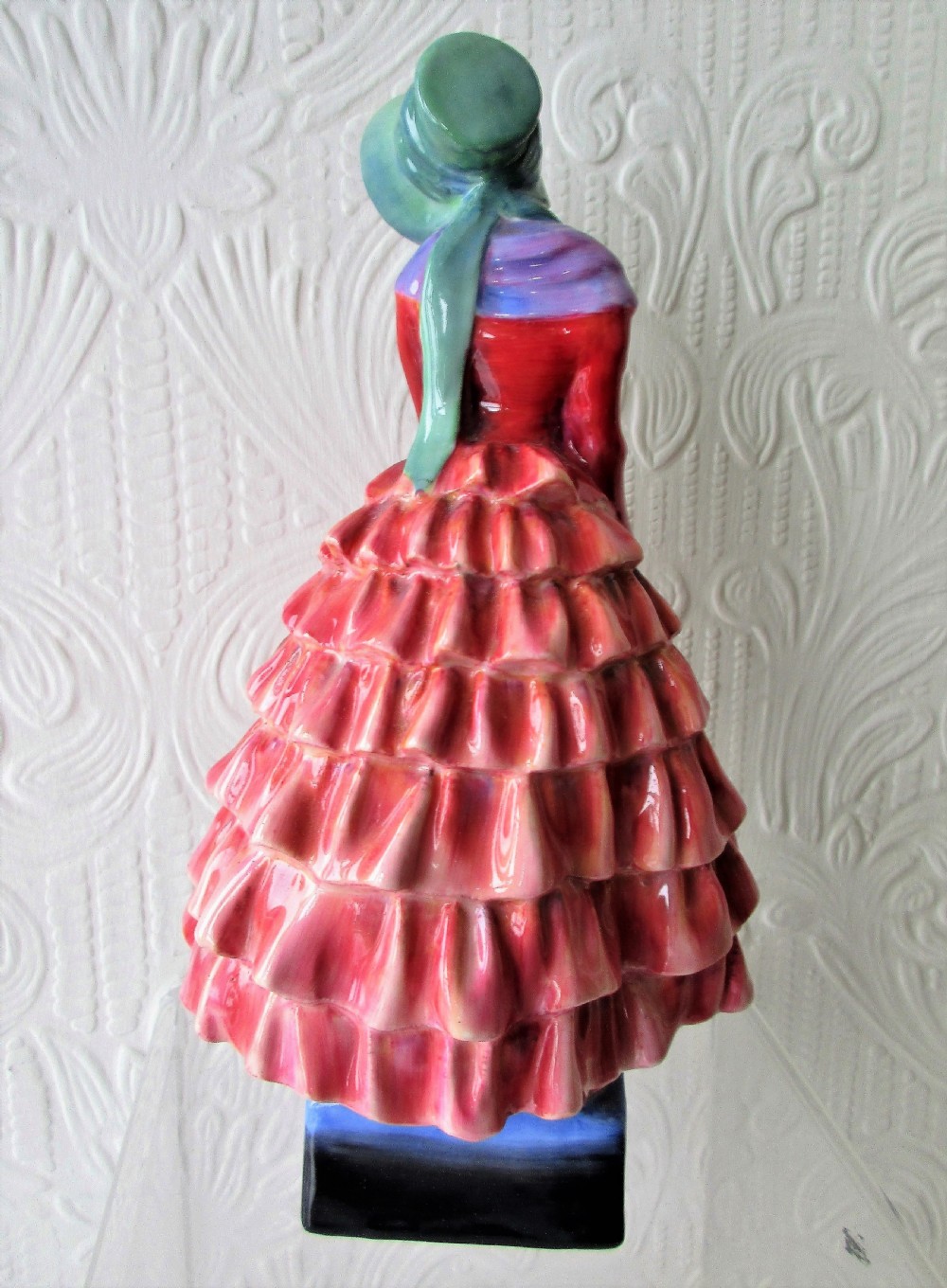 A Royal Doulton porcelain figurine titled Priscilla depicting a lady in a red tiered dress and green bonnet holding a parasol. View III