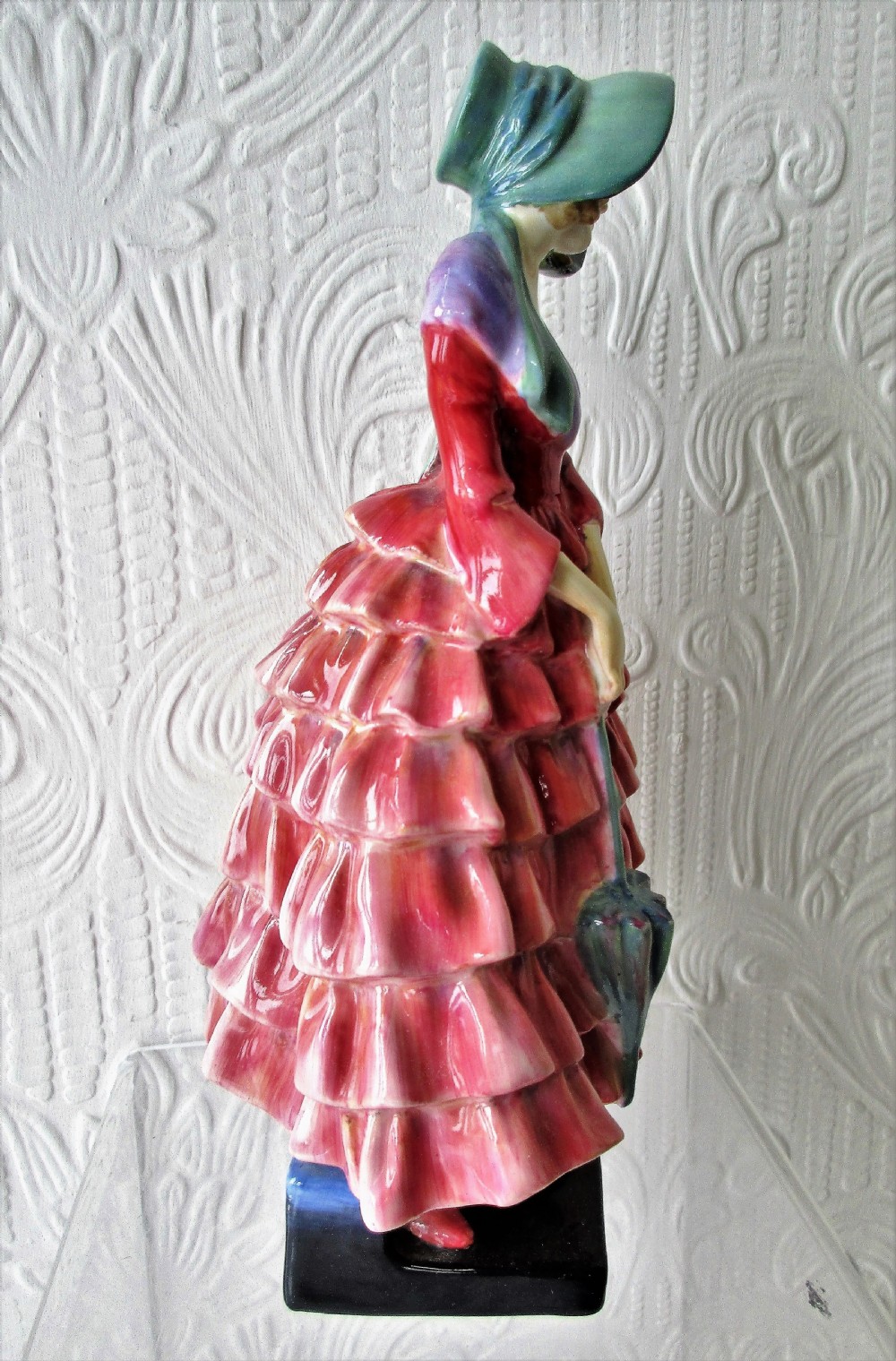 A Royal Doulton porcelain figurine titled Priscilla depicting a lady in a red tiered dress and green bonnet holding a parasol. View IV