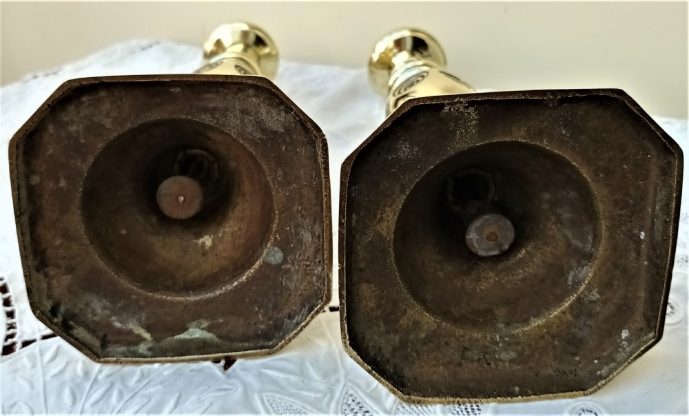 A pair of polished Victorian brass candlesticks featuring turned stems with concentric circle motifs and octagonal bases stamped with good luck text. View VI