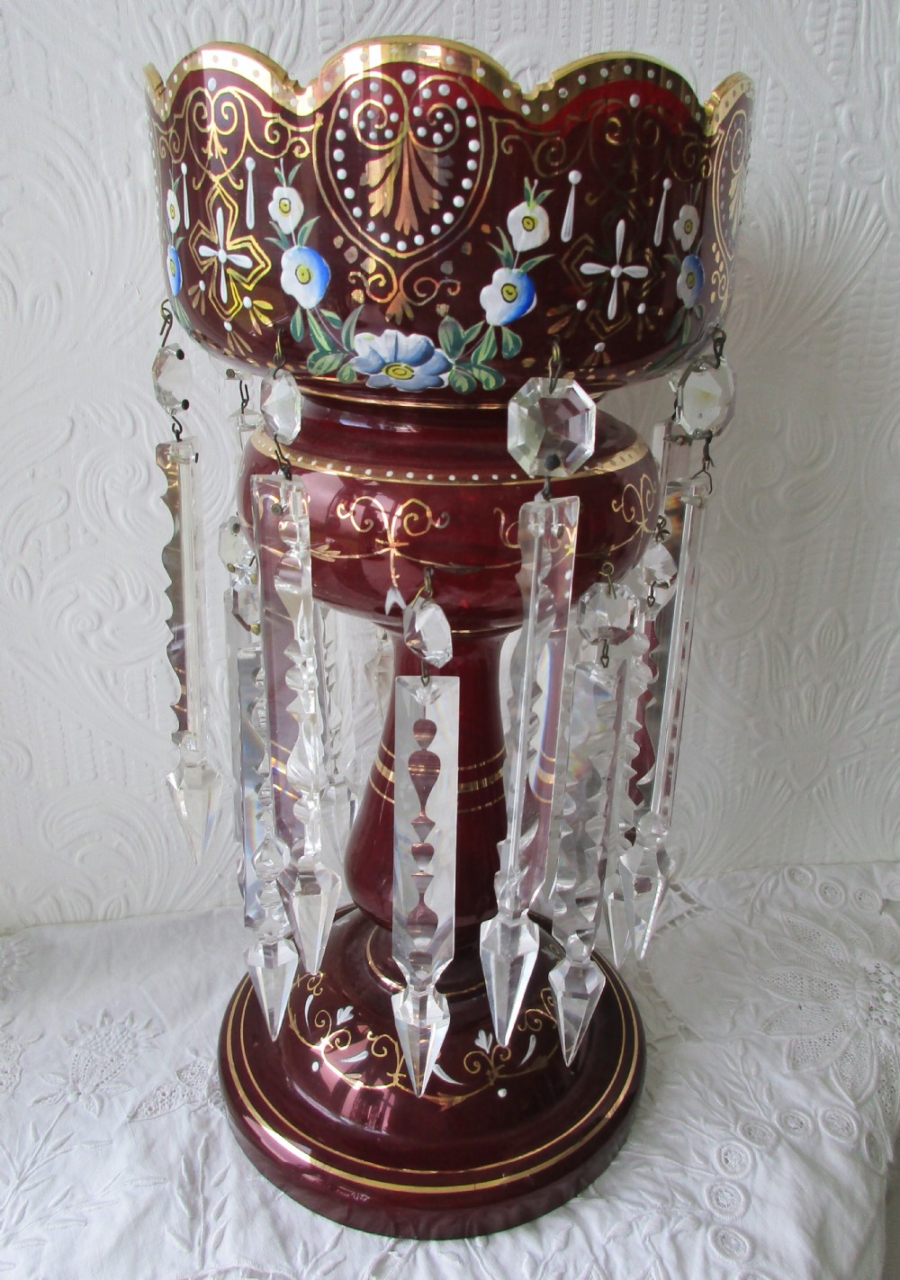 A pair of Victorian ruby glass lustres featuring hand-painted floral enamelling, gilt accents, and hanging clear crystal prisms. View II