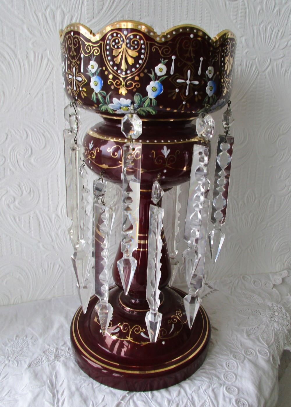 A pair of Victorian ruby glass lustres featuring hand-painted floral enamelling, gilt accents, and hanging clear crystal prisms. View IV