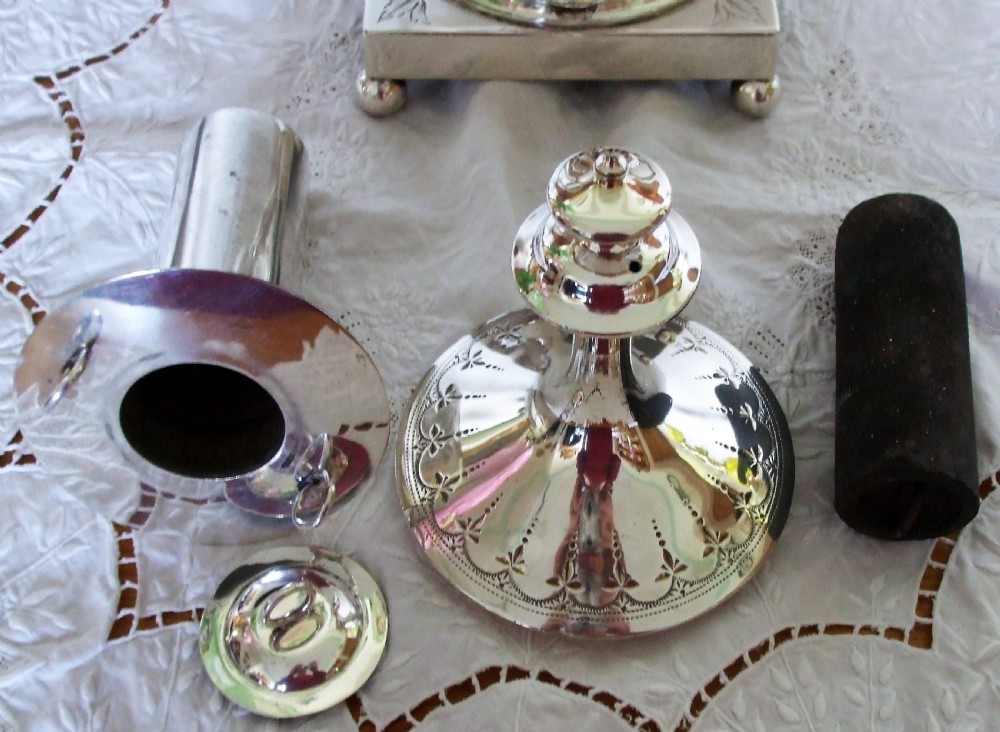 An Edwardian silver-plated samovar featuring engraved foliate motifs, high angular handles, a spigot tap, and a pedestal base resting on ball feet. View VII
