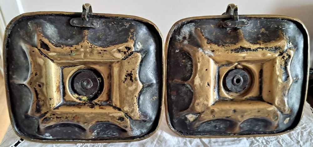 A pair of Victorian polished brass chambersticks with square dished trays, central socket columns, and side thumb handles. View V