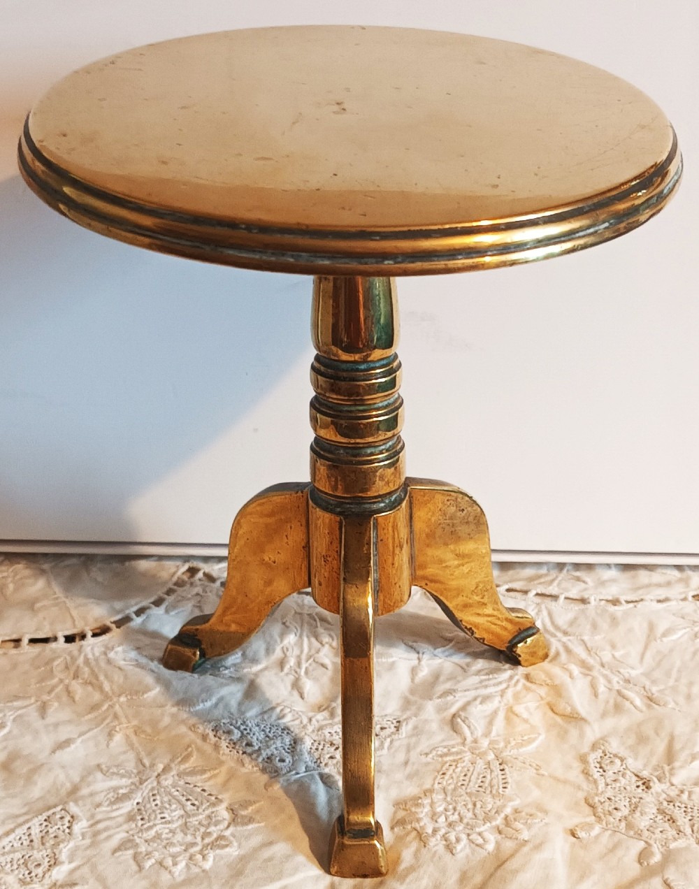 An antique Georgian brass candle reflector featuring a polished circular disc set on a turned column with a tripod base.