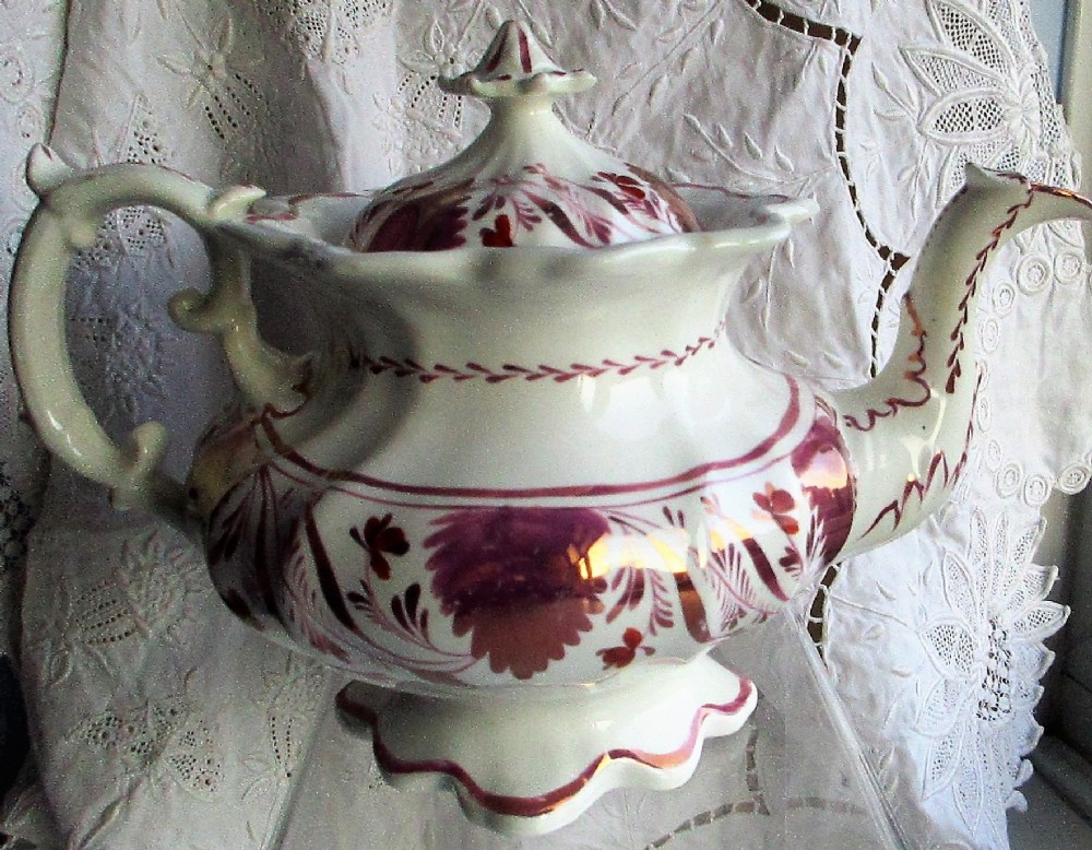 An antique white porcelain teapot decorated with pink iridescent metallic leaf motifs, a scalloped base, curved spout, and molded finial lid. View III