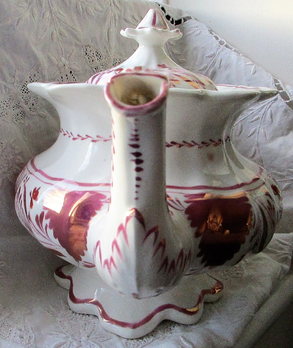 An antique white porcelain teapot decorated with pink iridescent metallic leaf motifs, a scalloped base, curved spout, and molded finial lid. View IV