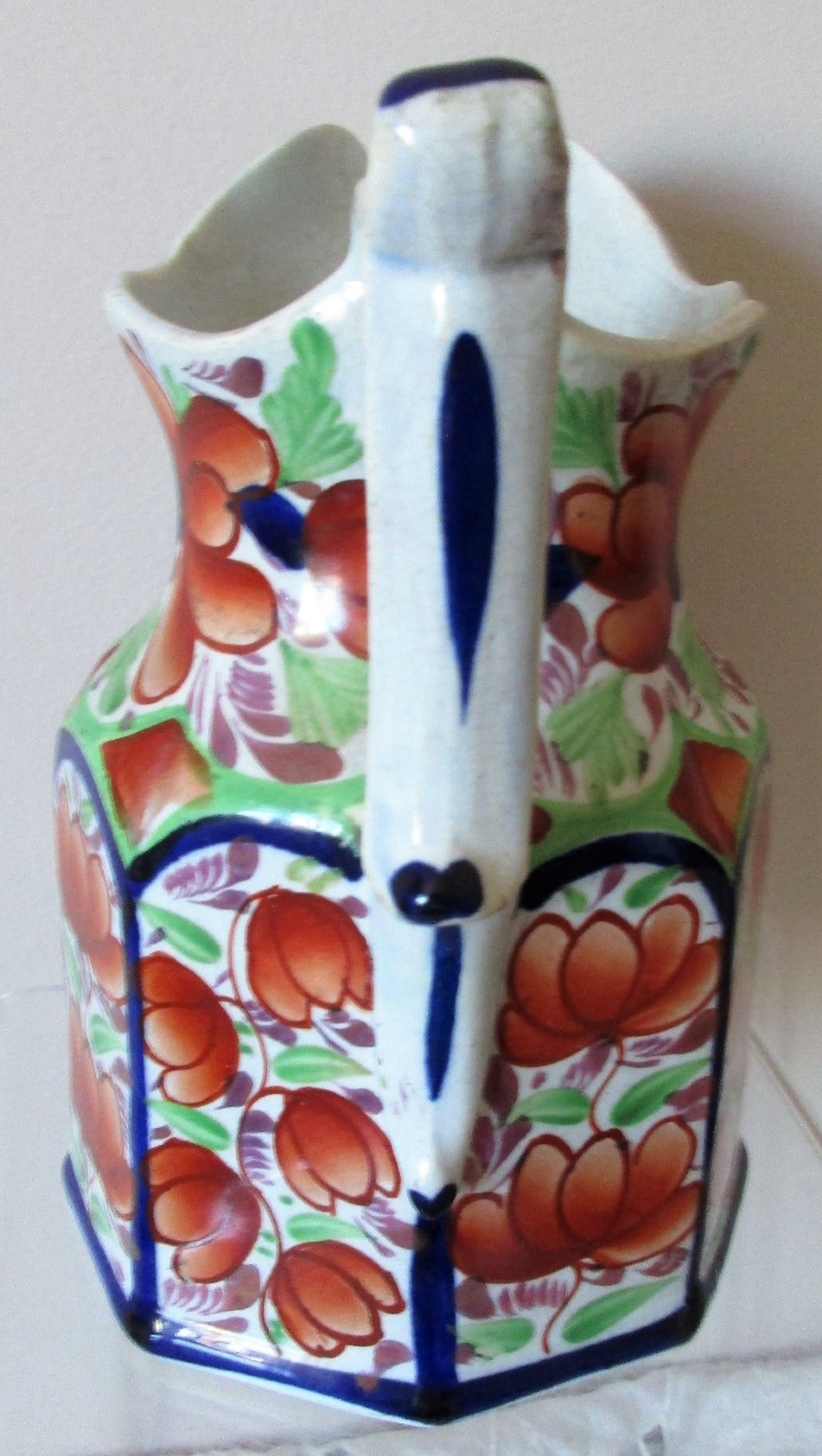 An octagonal Victorian Gaudy Welsh ceramic jug decorated with hand-painted rust-orange flowers, green leaves, and cobalt blue borders. View II