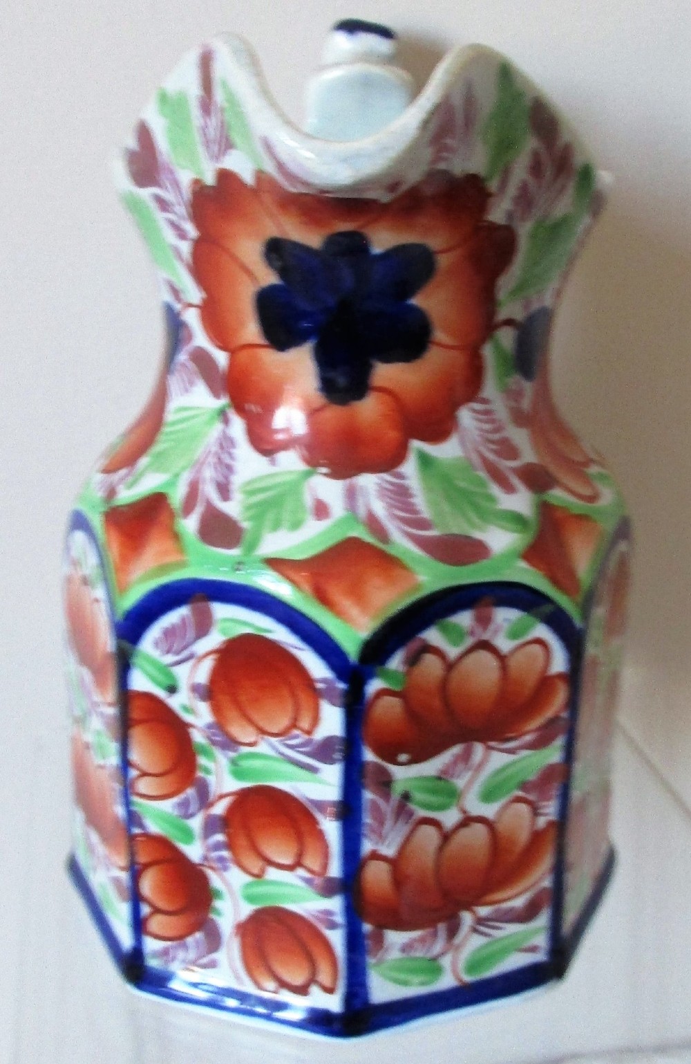 An octagonal Victorian Gaudy Welsh ceramic jug decorated with hand-painted rust-orange flowers, green leaves, and cobalt blue borders. View IV