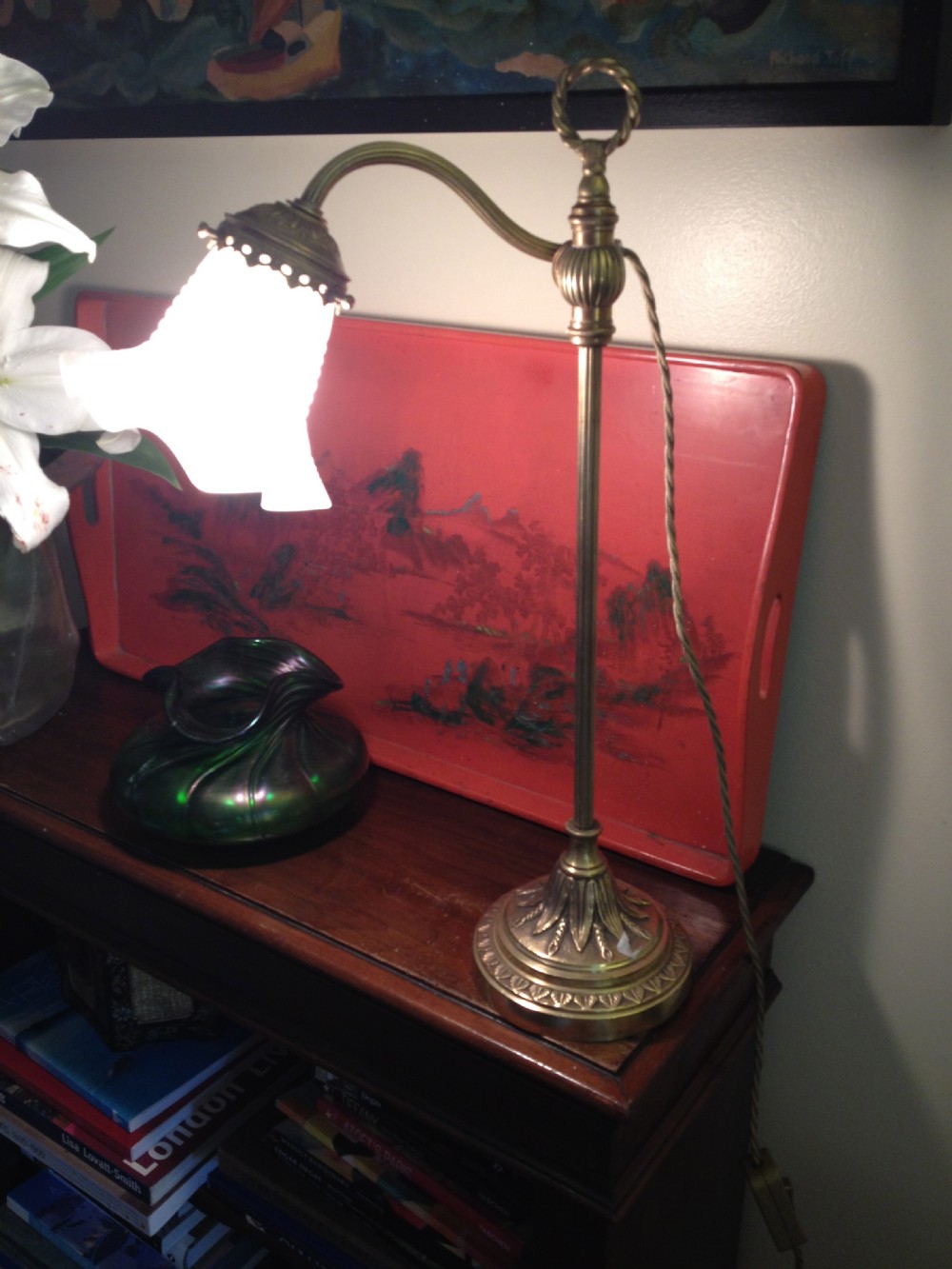 An antique adjustable bronze desk lamp featuring a cast leaf motif base, an arched arm, and a frosted white frilled glass shade.