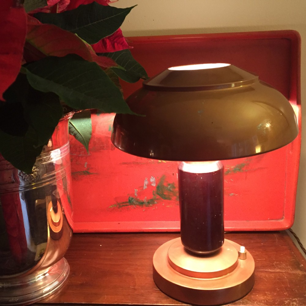 An Art Deco desk lamp featuring a bronze-toned dome shade, a dark macassar wood central pillar, and a stepped circular metal base with a integrated push switch.