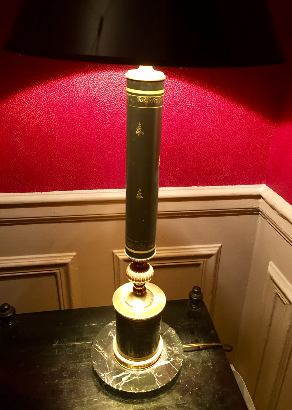 A tall black toleware column table lamp featuring gilded classical motifs, a fluted brass neck, and a circular marble base.