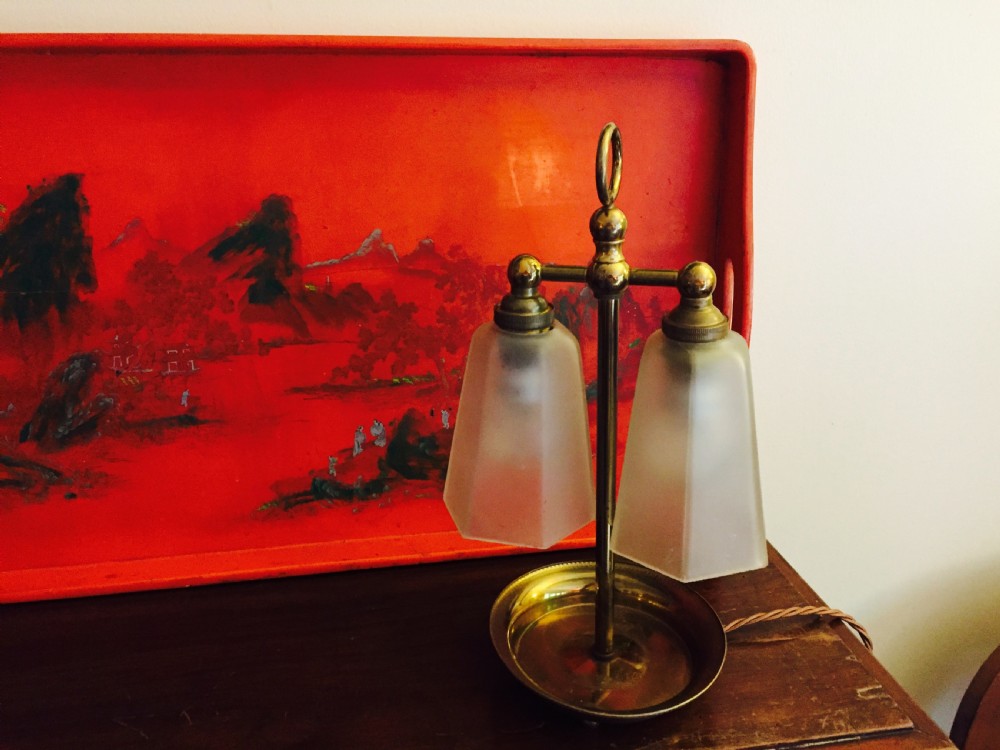 An Art Deco brass table lamp featuring twin arms with tapered frosted glass shades and a central loop handle above a dished base. View VII