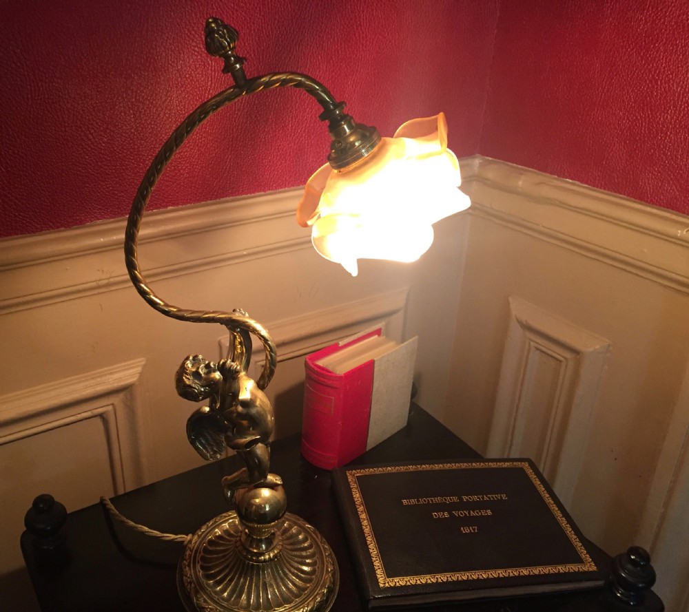 An antique brass and bronze table lamp featuring a cherub figure supporting a twisted gooseneck arm with a ribbed frosted glass shade. View II