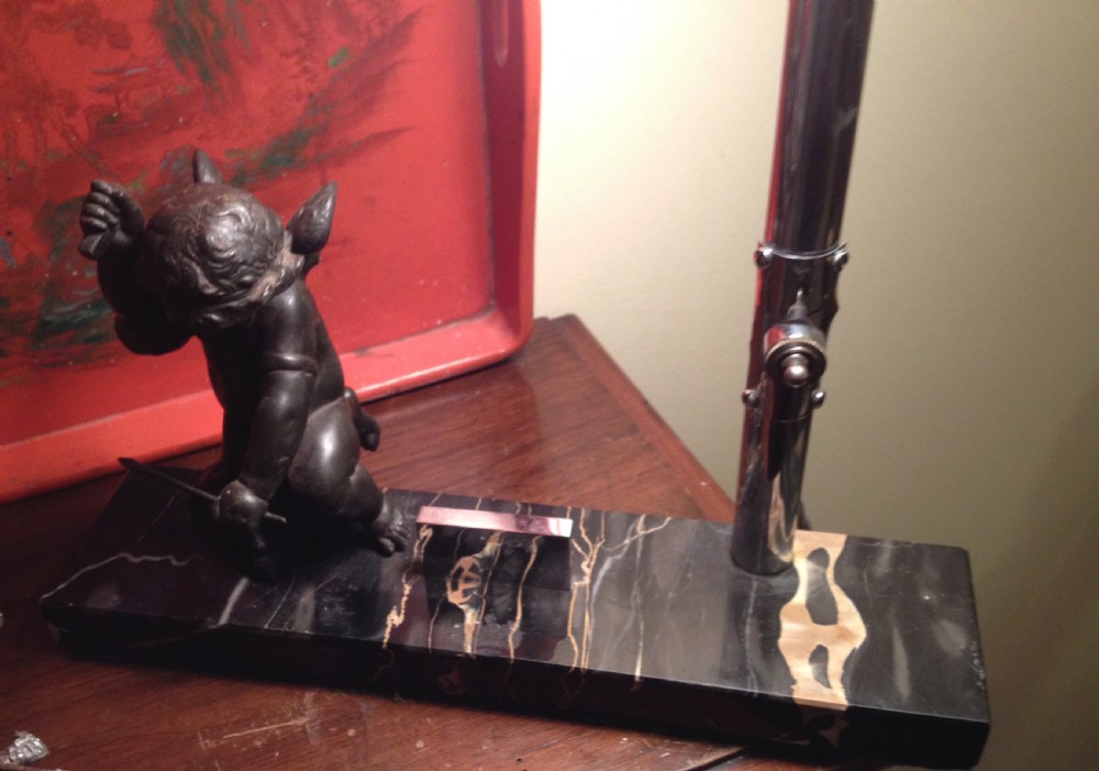 An Art Deco table lamp featuring a white glass flared shade on a chrome stem, mounted on a veined black marble base beside a small metal figure. View VI