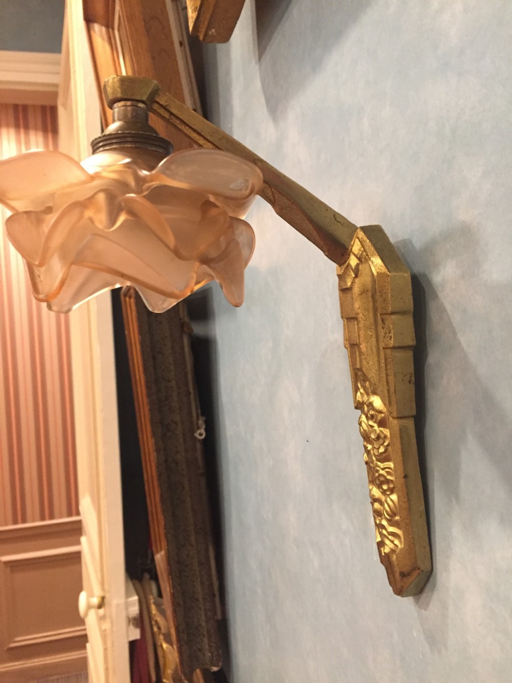 A 1920s Art Deco wall sconce featuring a cast bronze backplate with relief detailing and a stylized amber frosted glass shade. View IX