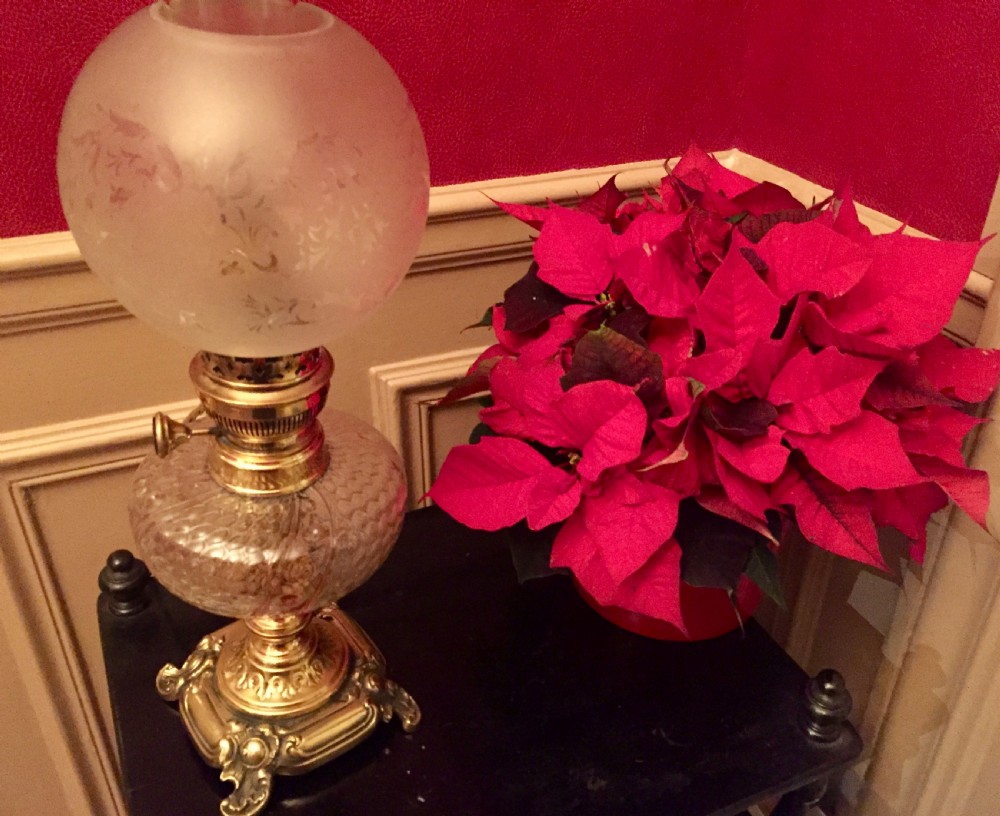 An Art Nouveau table lamp featuring an ornate cast brass base, a clear patterned glass reservoir, and a frosted spherical glass shade. View VI